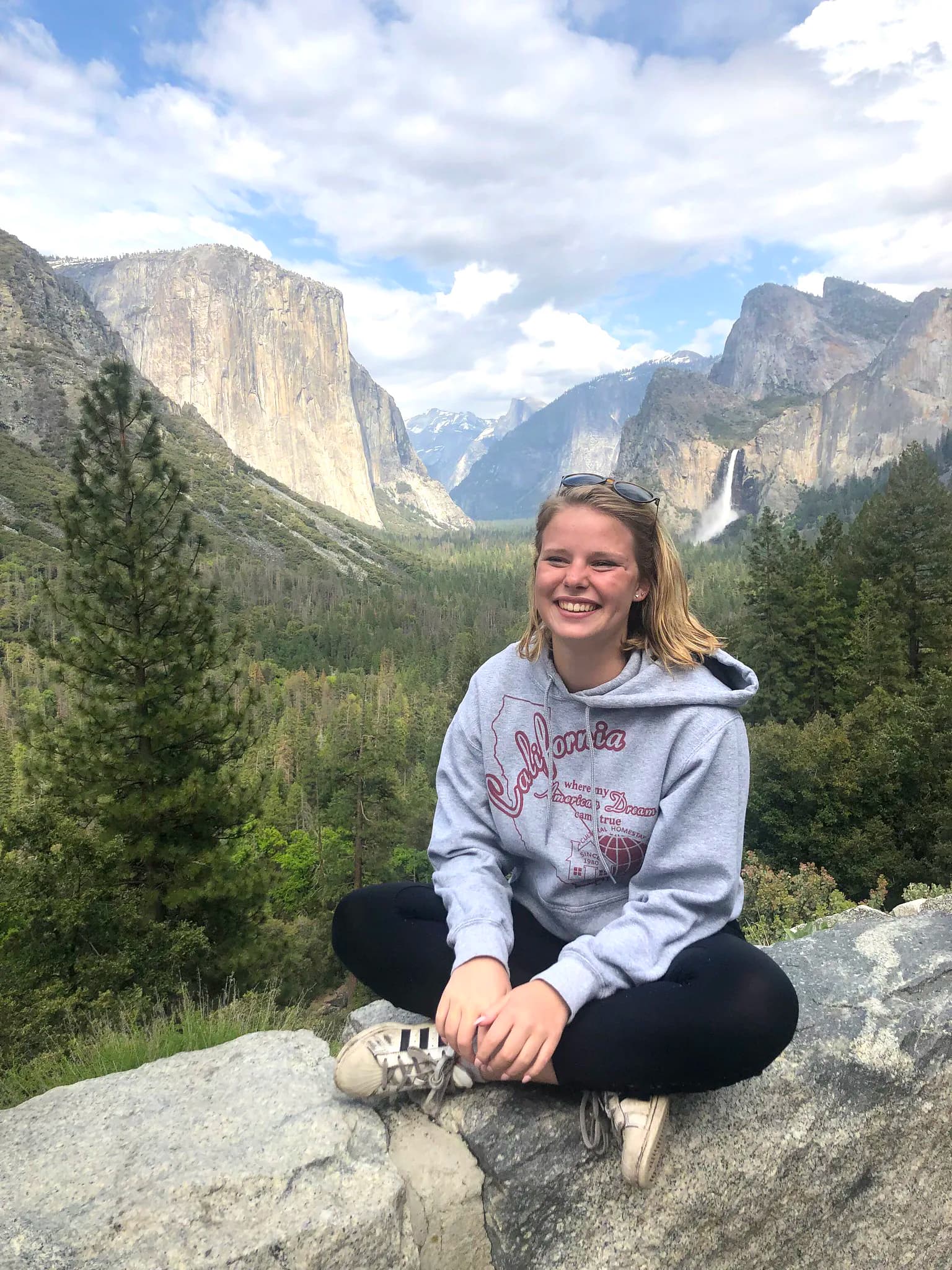 Una studentessa sorridente davanti a una vista mozzafiato nel Yosemite National Park, un'esperienza indimenticabile durante un anno scolastico negli USA.