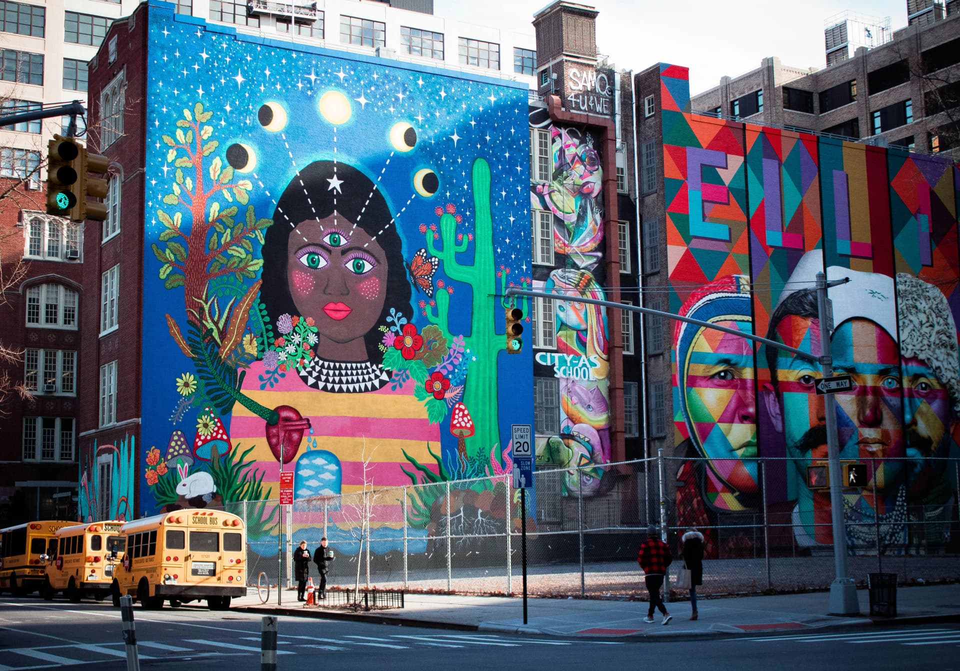 Murales colorati su edifici scolastici in una città degli Stati Uniti, con school bus parcheggiati, simbolo del sistema scolastico americano e della vita urbana.