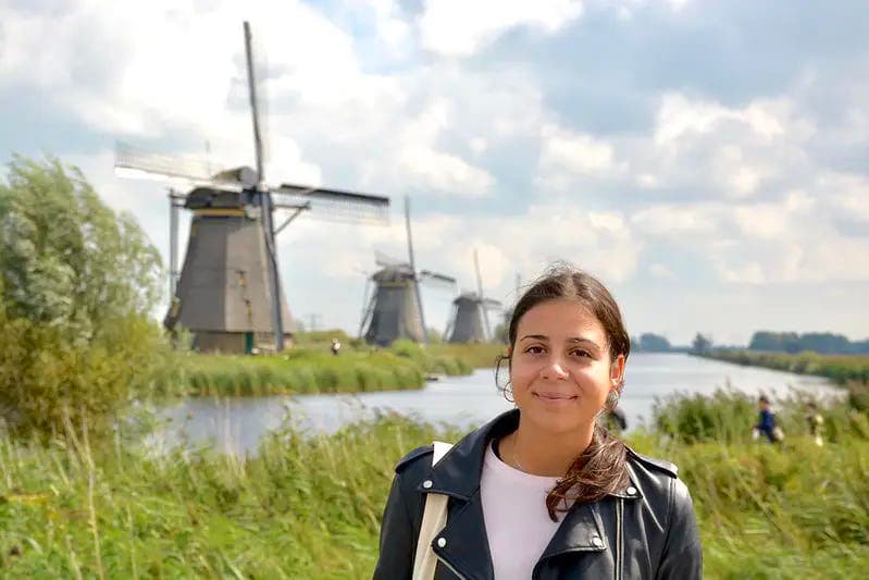 Ragazza all’aperto con mulini a vento sullo sfondo, simbolo della vita quotidiana e dell’esperienza di un anno all’estero nei Paesi Bassi.