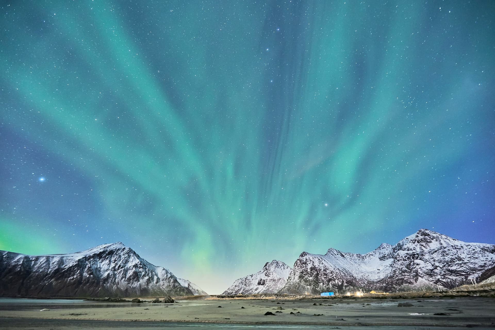 Vista notturna della maestosa aurora boreale che illumina il cielo sopra le montagne innevate in Norvegia, un'esperienza unica durante l’anno all’estero.