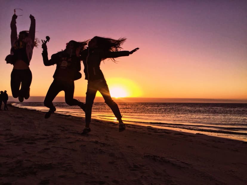 Ragazzi saltano sulla spiaggia al tramonto durante un soggiorno linguistico in Australia