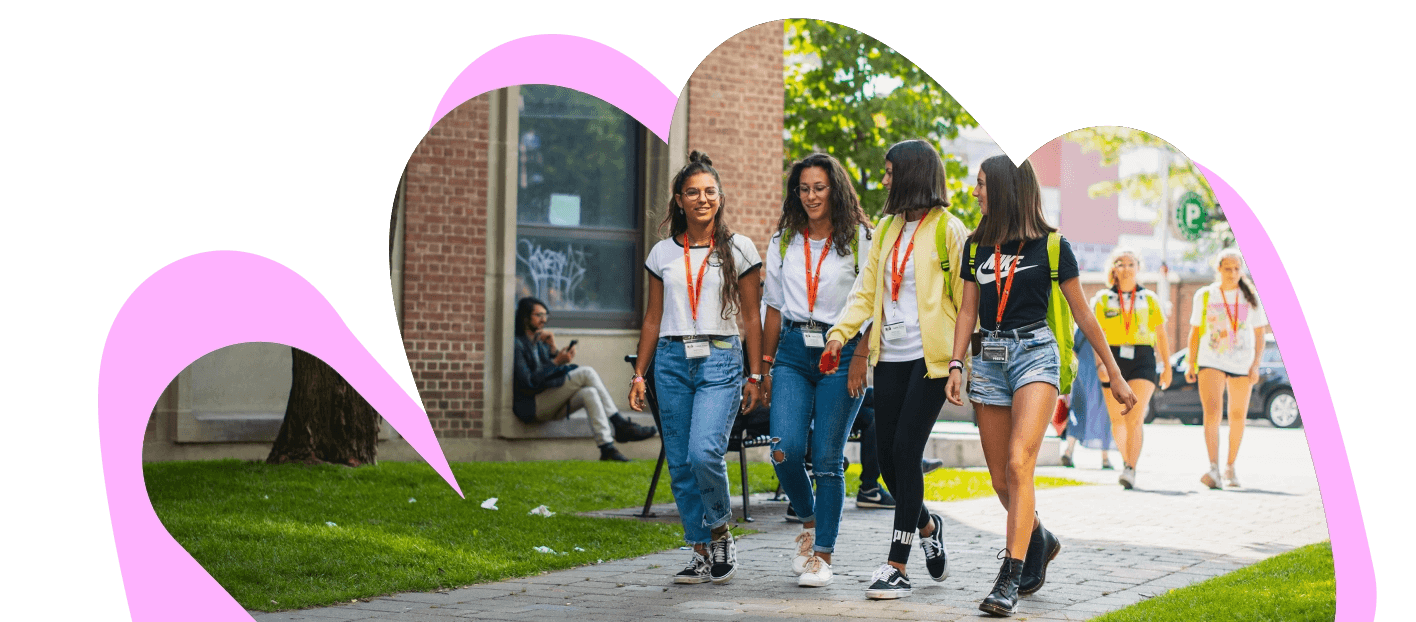 Gruppo di studenti che cammina all’interno di un campus universitario durante una vacanza studio, in un’atmosfera estiva e internazionale