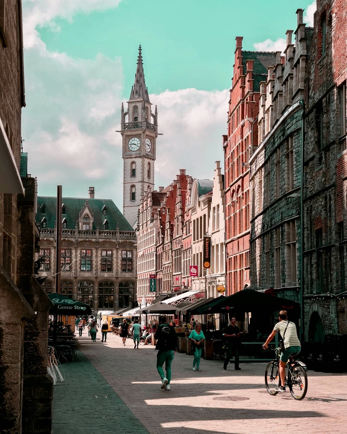 Studente che passeggia per il centro storico di Gent, ammirando l'architettura medievale e le piazze tipiche del Belgio durante il suo anno all'estero.