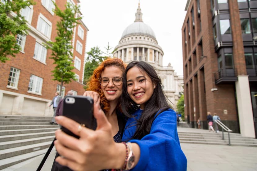 Due ragazze scattano un selfie davanti alla Cattedrale di St Paul a Londra durante un viaggio studio in Inghilterra
